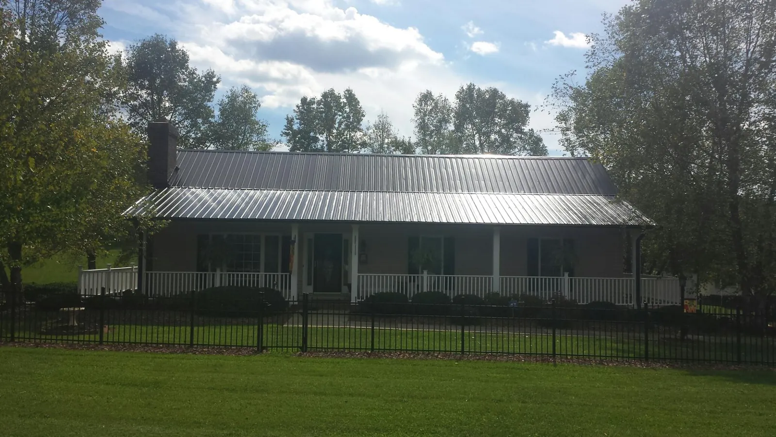 Gray metal roof on a brick ranch with a full width front porch — Gutter Guard Installation work by our crew in Tallassee