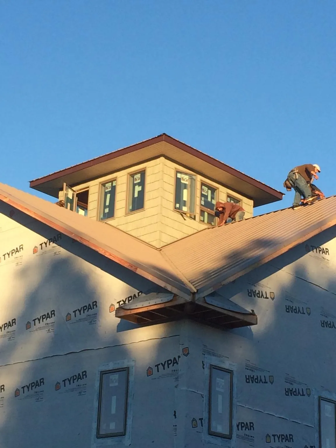 Roofers working around a rooftop cupola on a new metal roof at sunset — Roof Waterproofing in Tallassee by Roofing Brothers